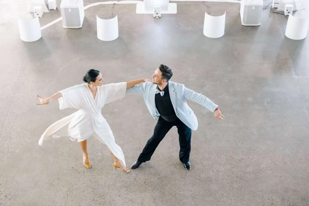 A couple practicing social ballroom dance together in a bright studio