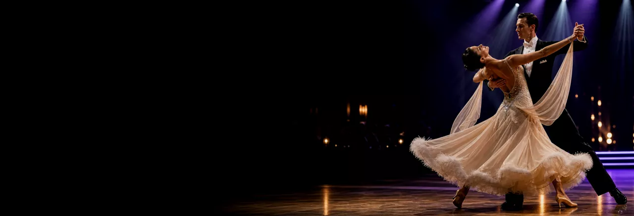 A ballroom dance couple performing beneath stage lights